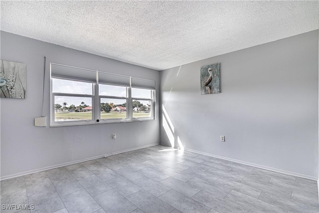 empty room with a textured ceiling and baseboards