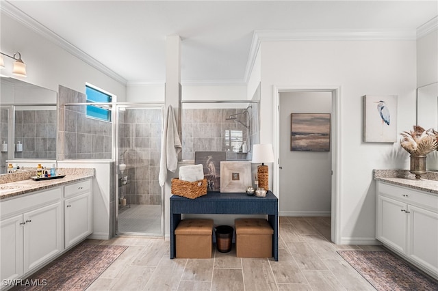 bathroom featuring a stall shower, wood finish floors, two vanities, and ornamental molding