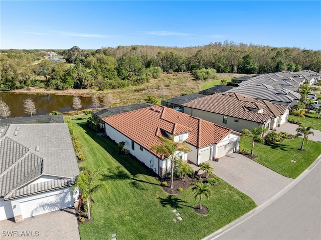 drone / aerial view featuring a view of trees, a water view, and a residential view