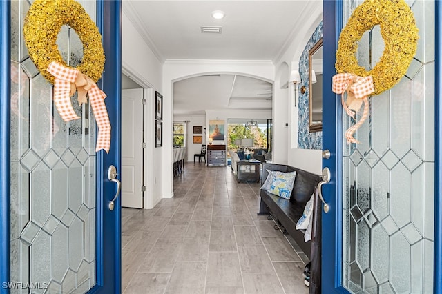 entrance foyer featuring visible vents, arched walkways, and crown molding