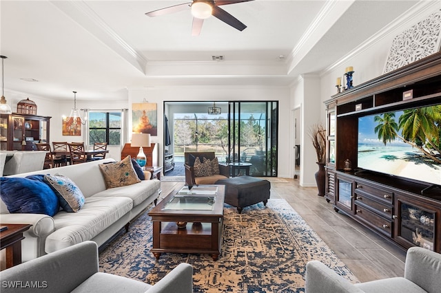 living room featuring a tray ceiling, visible vents, and ornamental molding