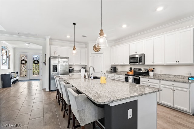 kitchen featuring crown molding, appliances with stainless steel finishes, french doors, arched walkways, and a sink