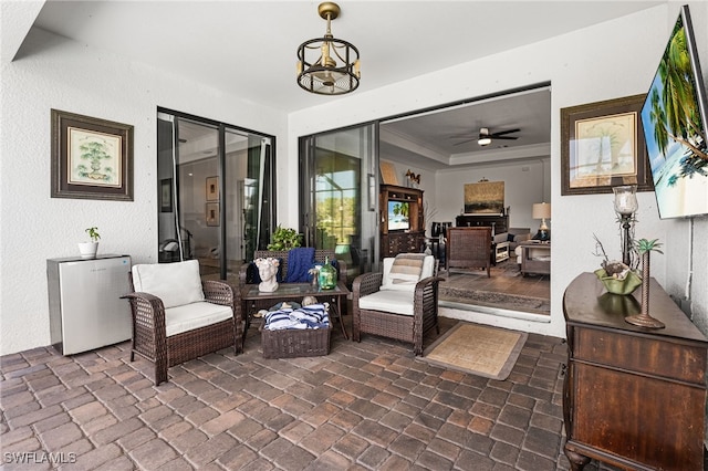 sitting room with a raised ceiling, crown molding, and a ceiling fan