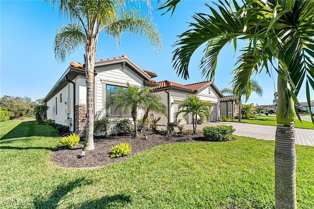 view of front facade featuring a tiled roof, driveway, an attached garage, and a front yard