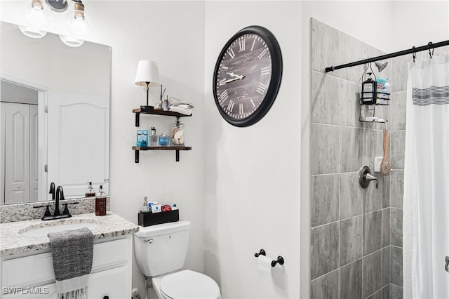 bathroom featuring vanity, toilet, and tiled shower