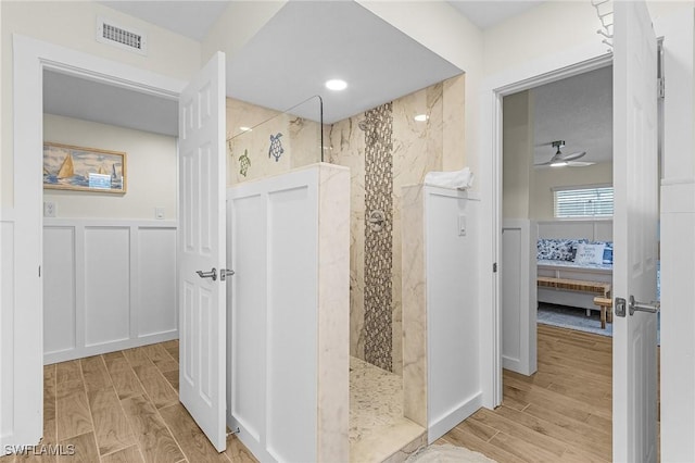 full bath with visible vents, connected bathroom, a walk in shower, wood finish floors, and a decorative wall