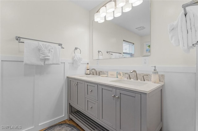 full bath with a sink, visible vents, wainscoting, and double vanity