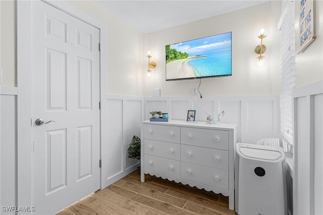 bathroom with wainscoting, wood tiled floor, and a decorative wall