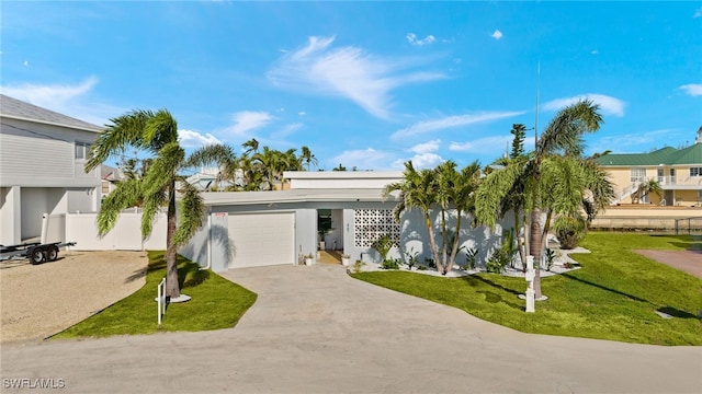 view of front of house with stucco siding, driveway, fence, a front yard, and a garage