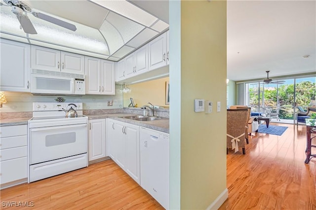 kitchen with white appliances, a sink, white cabinetry, and light wood-style floors