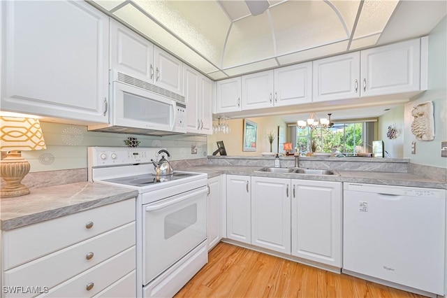 kitchen featuring white appliances, light countertops, a sink, and light wood finished floors