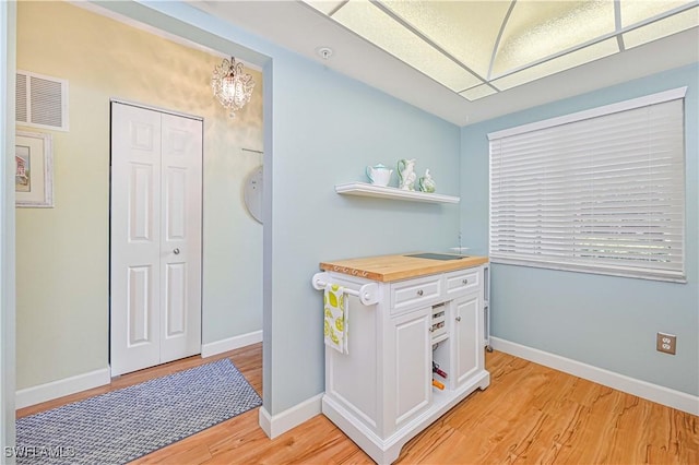 interior space with white cabinets, light wood-style floors, visible vents, and open shelves