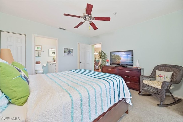 bedroom featuring ensuite bathroom, light colored carpet, a ceiling fan, visible vents, and a closet