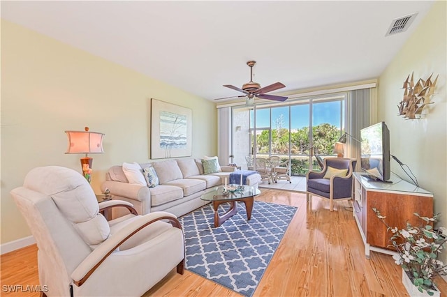 living area with light wood-type flooring, ceiling fan, visible vents, and baseboards