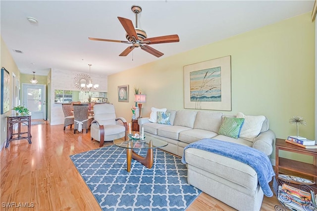 living room with visible vents, wood finished floors, and ceiling fan with notable chandelier