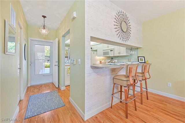 foyer entrance featuring light wood-style flooring, baseboards, and a chandelier