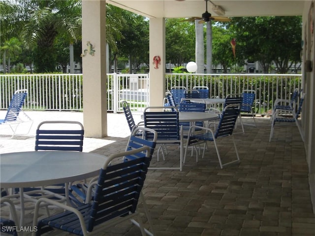 view of patio featuring ceiling fan, outdoor dining area, and fence