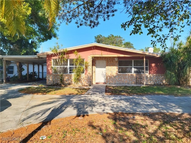 view of front of house featuring an attached carport, stone siding, and driveway