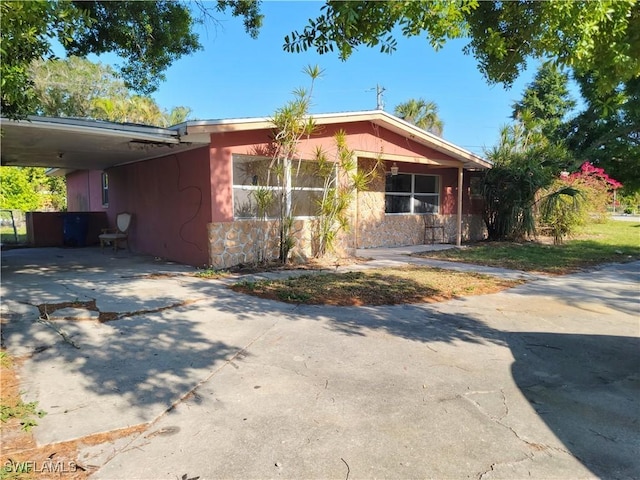 single story home featuring a carport, stone siding, and concrete driveway