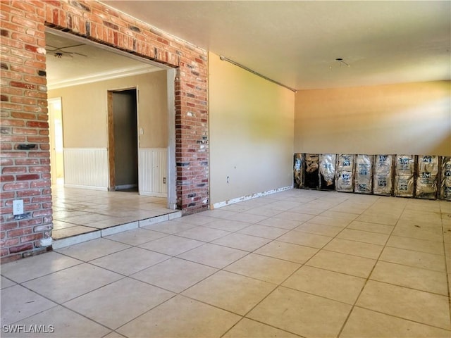 tiled empty room with crown molding and wainscoting