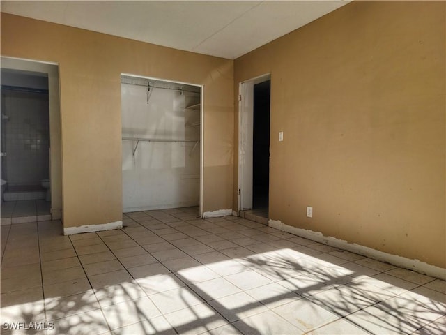 unfurnished bedroom with light tile patterned floors, a closet, and baseboards