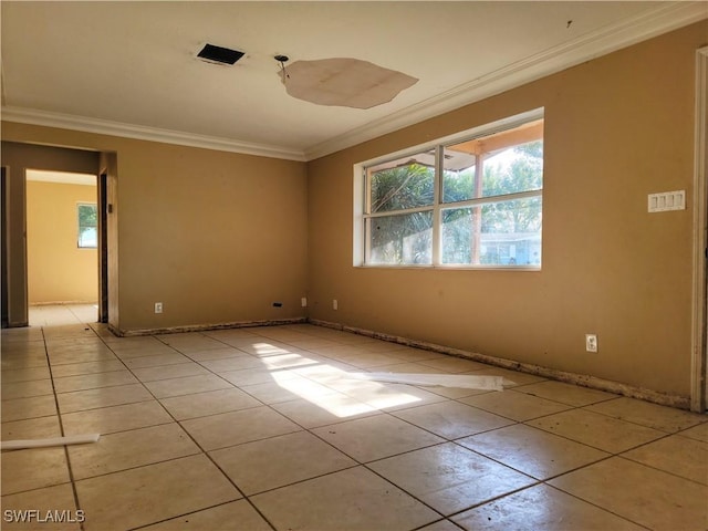 empty room featuring light tile patterned floors, baseboards, and crown molding