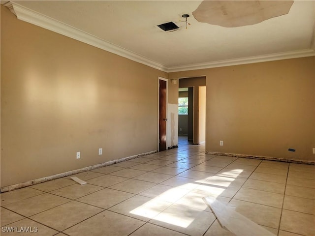 empty room with light tile patterned floors, baseboards, and crown molding