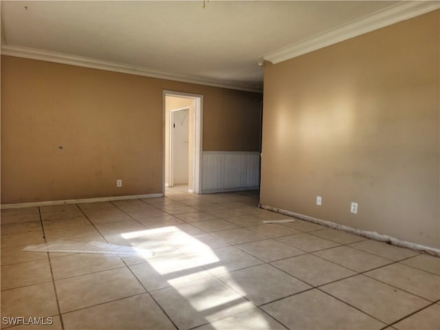 spare room featuring baseboards, ornamental molding, and tile patterned floors