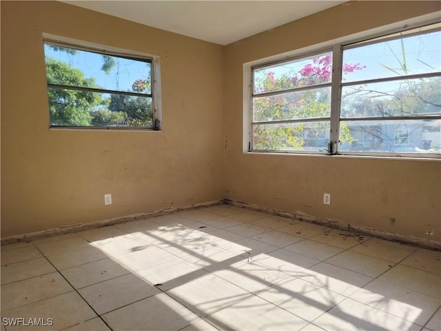 empty room featuring a healthy amount of sunlight and light tile patterned floors