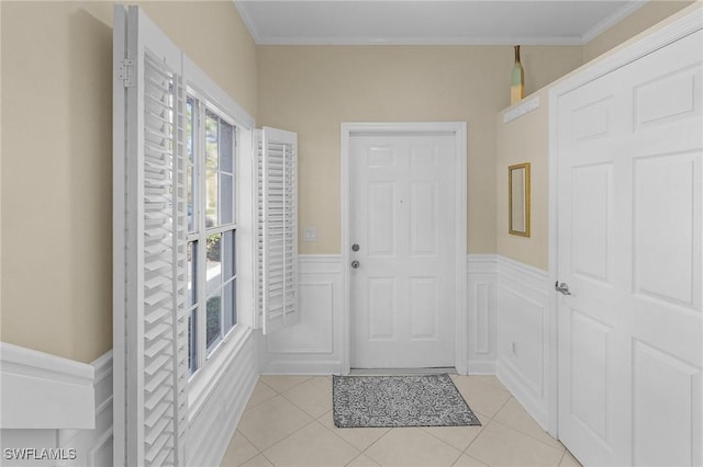 foyer entrance with a wainscoted wall, crown molding, and light tile patterned floors