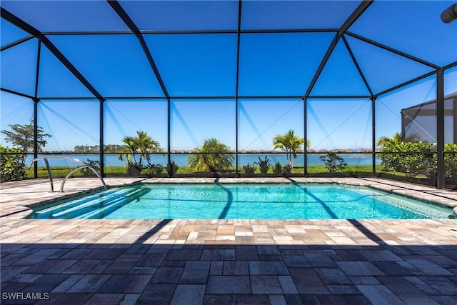 pool featuring glass enclosure, a patio area, and a water view