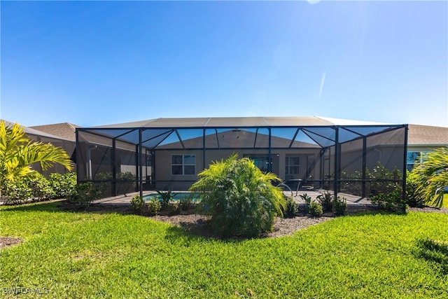 back of house featuring glass enclosure, a lawn, a patio, and an outdoor pool