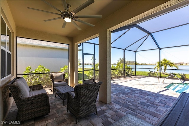 view of patio / terrace featuring a water view, glass enclosure, and ceiling fan