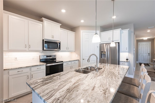 kitchen with a breakfast bar, tasteful backsplash, appliances with stainless steel finishes, white cabinets, and a sink