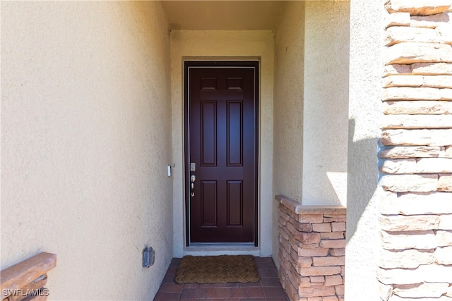 doorway to property featuring stone siding and stucco siding