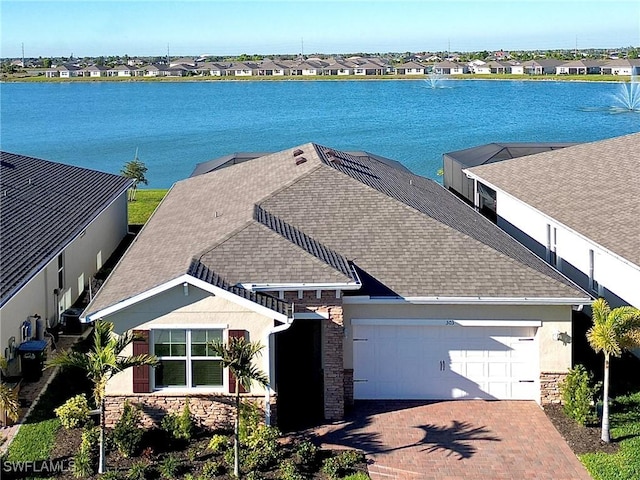 view of front of property featuring a garage, a residential view, stone siding, and a water view