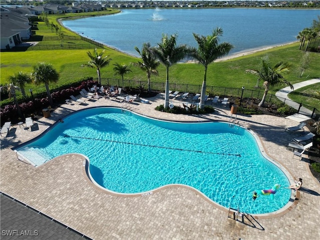 community pool with a yard, a patio area, fence, and a water view