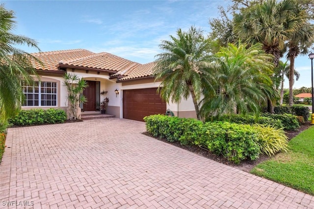 12604 Wildcat Cove Cir, Estero, FL 33928 - mediterranean / spanish house featuring a garage, stucco siding, a tile roof, and decorative driveway
