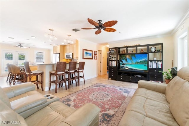 living area with light tile patterned flooring, a ceiling fan, visible vents, and ornamental molding