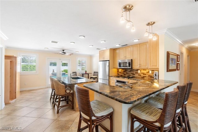 kitchen with light brown cabinets, appliances with stainless steel finishes, a kitchen bar, crown molding, and backsplash