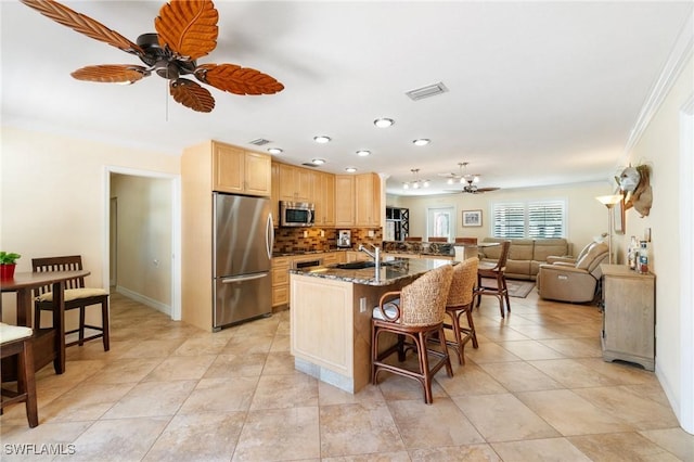 kitchen with visible vents, light brown cabinets, a breakfast bar, ornamental molding, and stainless steel appliances