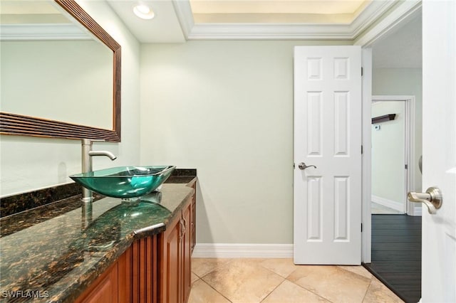 bathroom featuring tile patterned flooring, vanity, crown molding, and baseboards