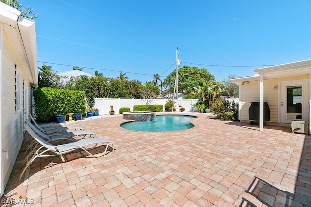 view of swimming pool featuring grilling area, a pool with connected hot tub, a fenced backyard, and a patio area
