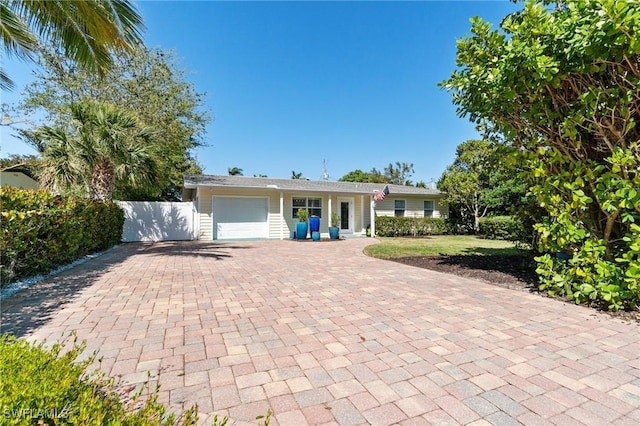 single story home with a garage, decorative driveway, and fence