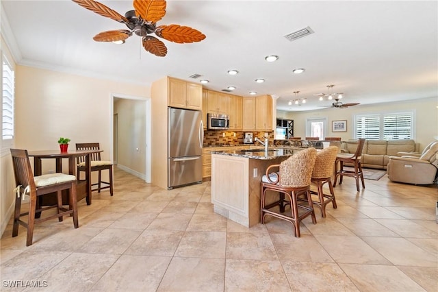 kitchen featuring a ceiling fan, visible vents, a breakfast bar, light brown cabinetry, and appliances with stainless steel finishes