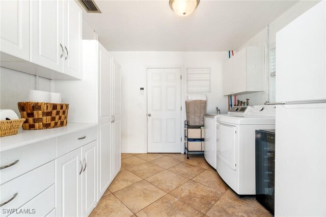 clothes washing area with washing machine and clothes dryer, visible vents, and cabinet space