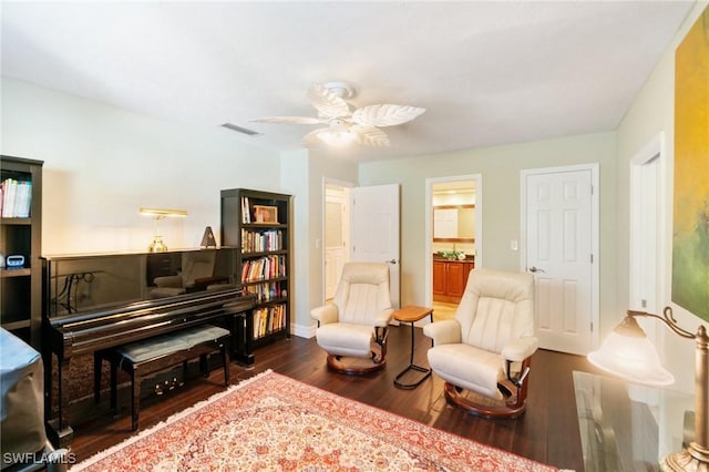 sitting room featuring visible vents, baseboards, wood finished floors, and a ceiling fan