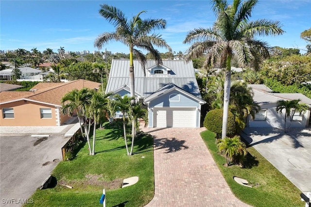 view of front of property with metal roof, a front lawn, decorative driveway, and an attached garage