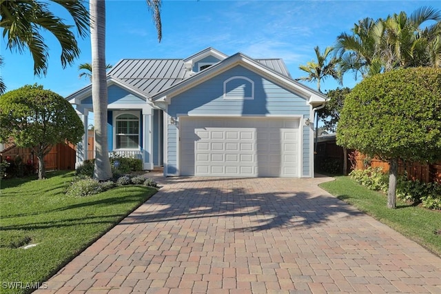 view of front of property with metal roof, a garage, fence, decorative driveway, and a standing seam roof