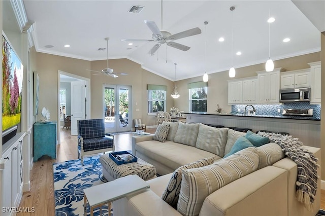 living room with vaulted ceiling, ornamental molding, light wood-type flooring, and visible vents